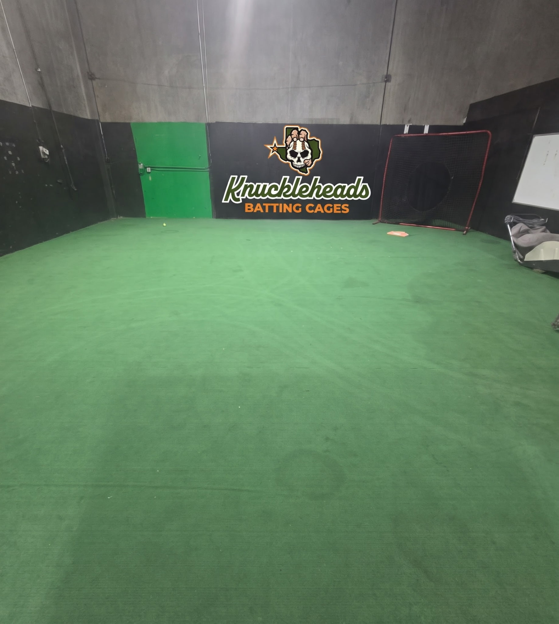 Green turf and the Knuckleheads Batting Cages logo inside the facility